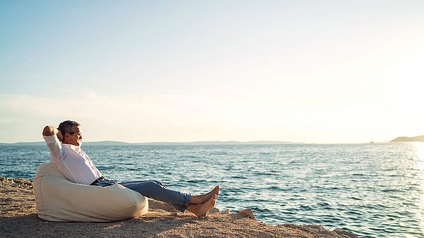 Rentner entspannt am Meer in einem Sandsack