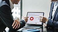 Individuelle Finanzplanung mit kostenloser Depotanalyse - Hypo Vorarlberg Zwei Männer zeigen auf einen Bildschirm und analysieren eine Depotchart.