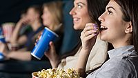 Kinoevent - Hypo Vorarlberg Frau sitzt im Kino und isst Popcorn