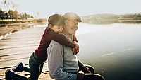 Enkel umarmt Opa und sitzen am See